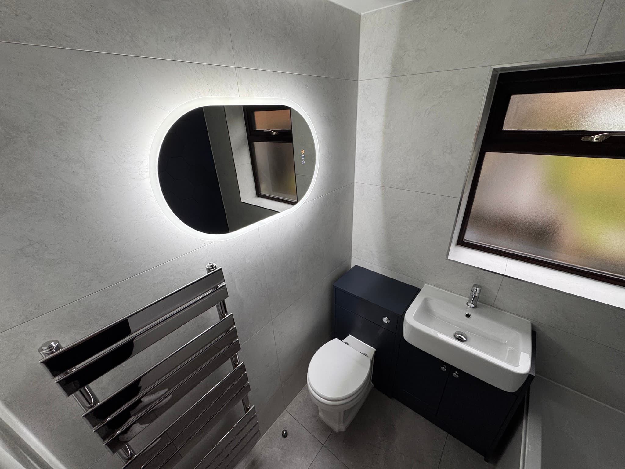 En-suite bathroom with sand wave-texture tiles, floating dark wood vanity, and bronze heated towel rail