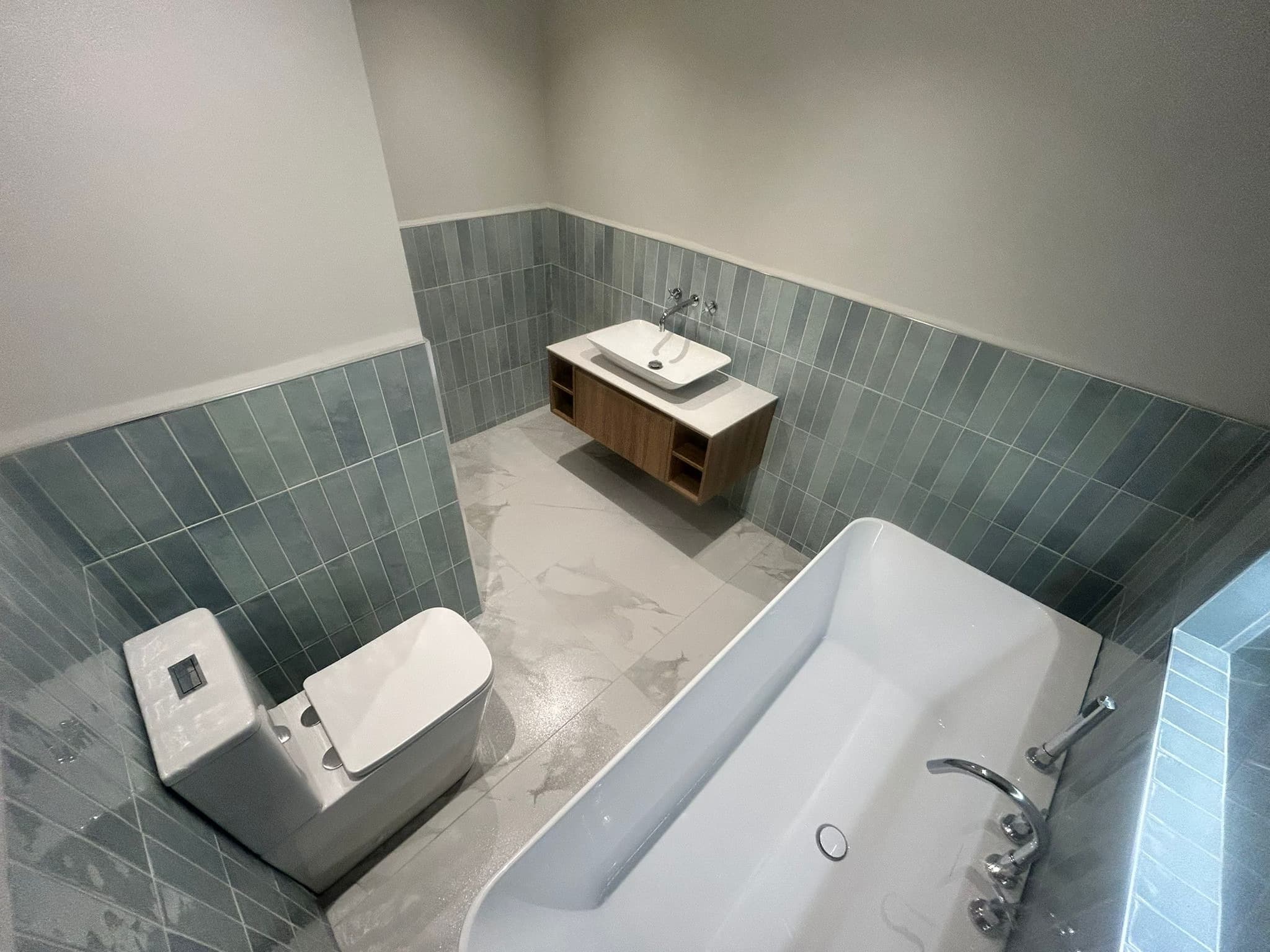 Full bathroom with blue-grey subway tiles and marble-effect floor