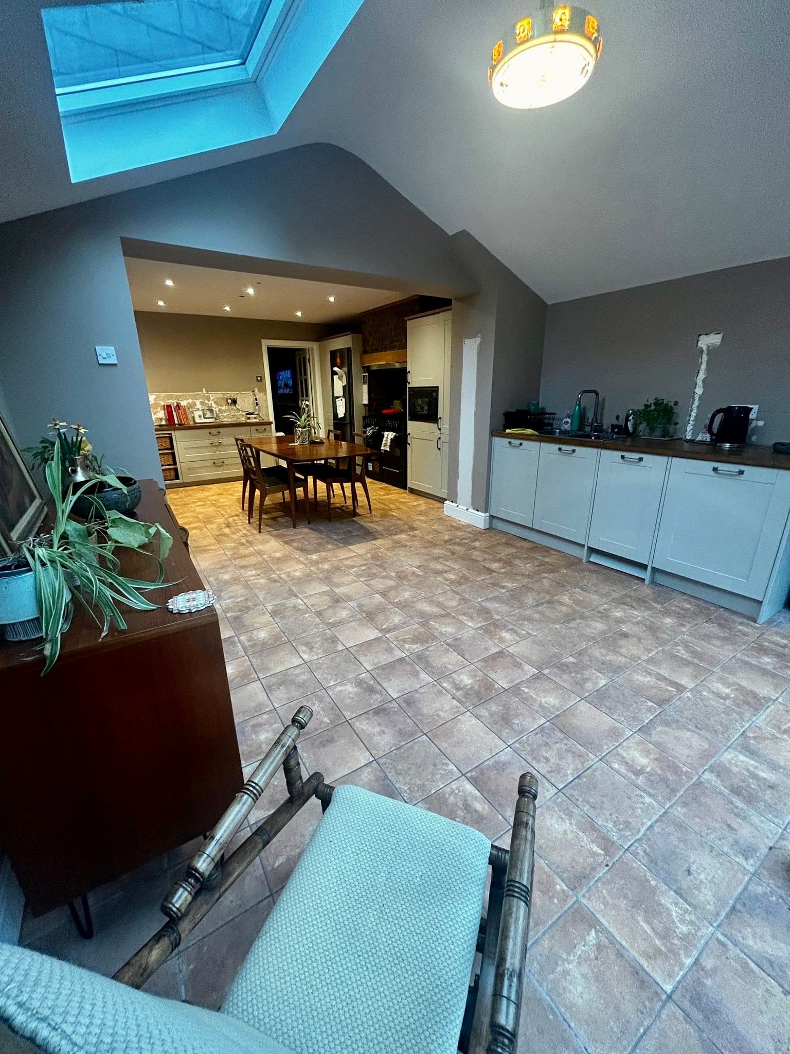 Large open-plan kitchen extension with taupe travertine-effect floor tiles