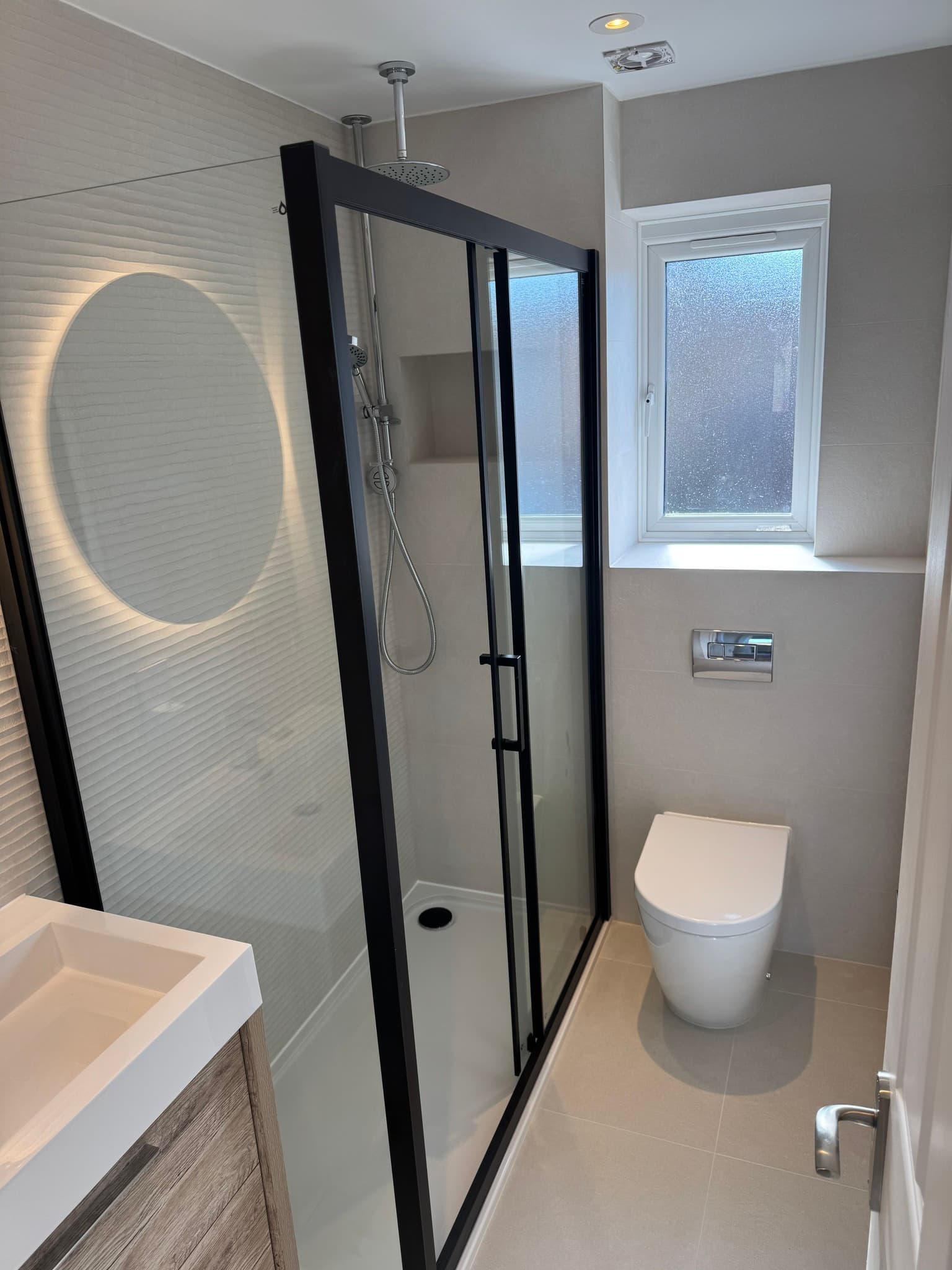 Sleek bathroom with white wave-texture tiles and large black-framed walk-in shower