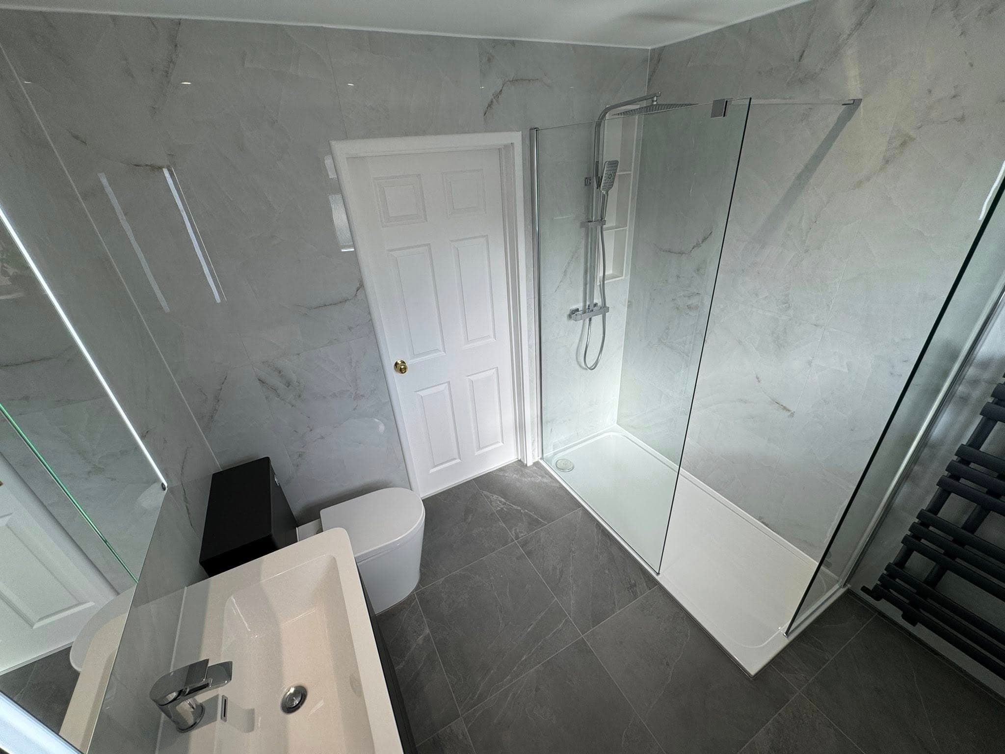 Full bathroom with Calacatta marble-effect wall tiles and contrasting dark floor tiles