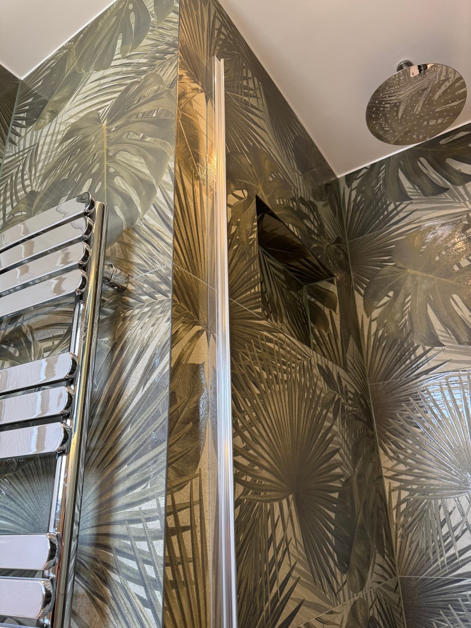 Shower wall fully tiled in tropical leaf-print ceramic tiles